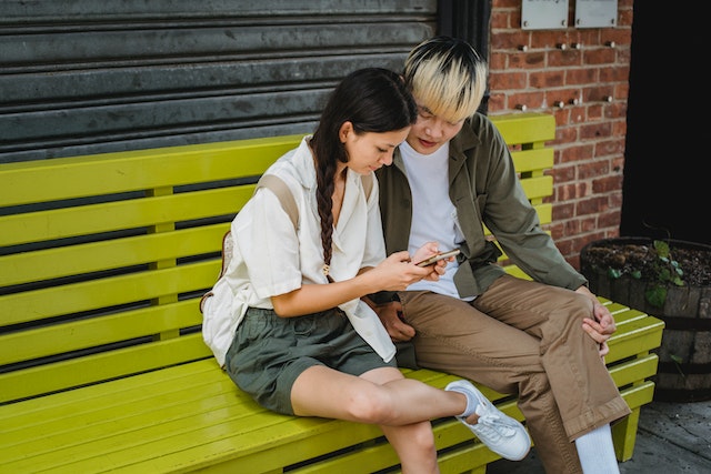 A couple on a street bench checking out the latest posts on social media. 
