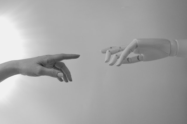 Die Hände eines Menschen und eines Roboters reichen sich die Hände, um einander zu treffen. 