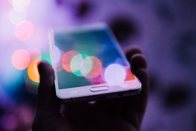 Abstract image of an unseen person holding up their smartphone with bokeh lens flare.