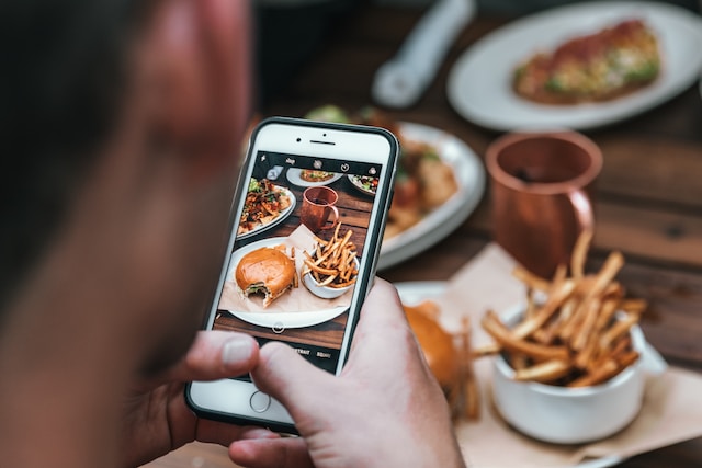 Een gebruiker die een foto maakt van het eten dat hij eet om te uploaden op zijn Instagram. 