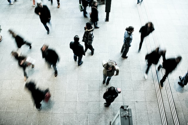 Folla di persone indaffarate che camminano e utilizzano dispositivi mobili.