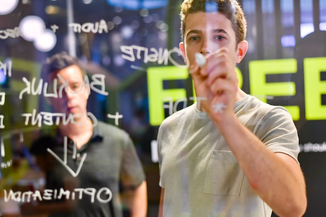 Man writing with white marker on a glass wall