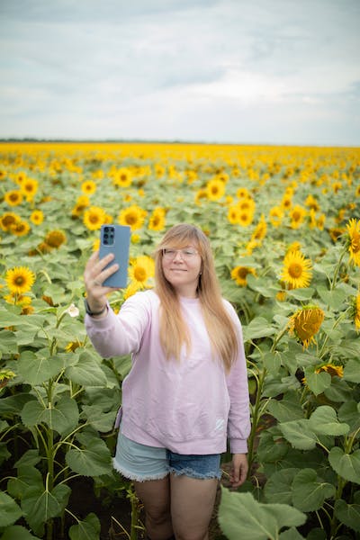 Mädchen in einem Sonnenblumenfeld hält ein Telefon