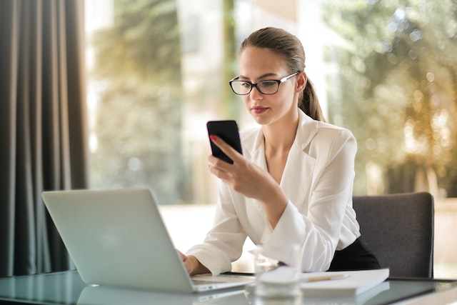 Een vrouw controleert haar Instagram account op haar mobiele telefoon terwijl ze aan het werk is. 