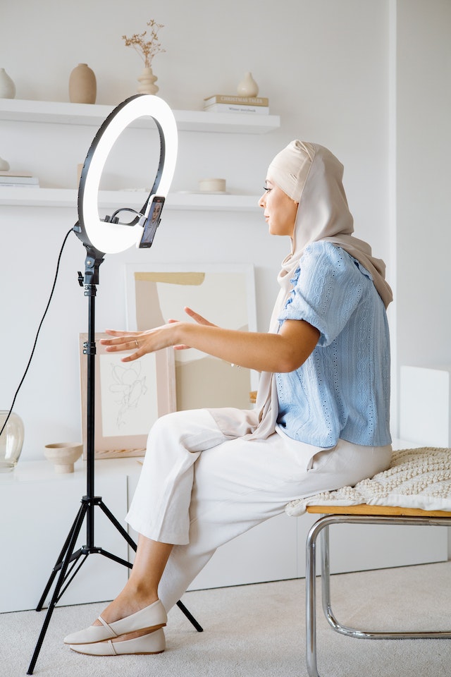 A woman wearing a hijab is recording a live video.