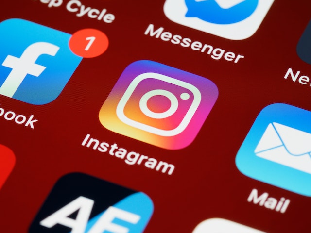 Grande plano da aplicação Instagram num smartphone ao lado de outras aplicações de redes sociais.  