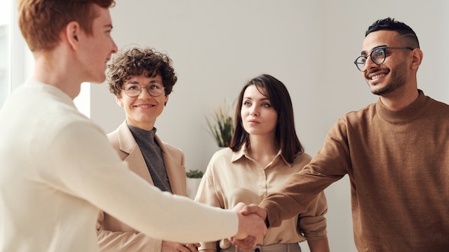 An influencer shaking hands with a marketing manager to seal their brand deal contract.