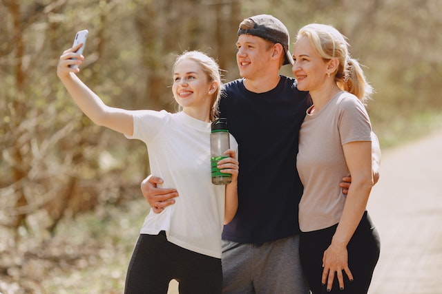 Een influencer maakt een groepsfoto met een groep, terwijl hij een waterfles vasthoudt.