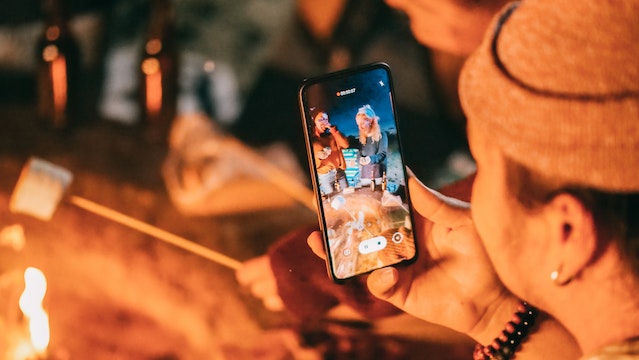 Homem gravando um vídeo vertical de seus amigos para usar como conteúdo Instagram Carretel.