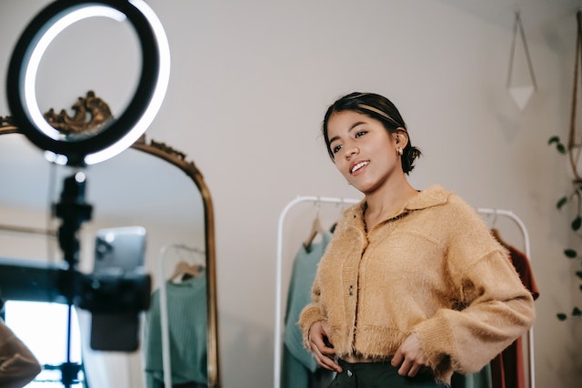 A lady recording a video in front of a ring light.