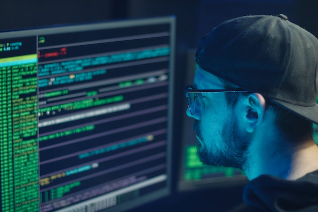 Man looking over developer code on a computer screen at night.