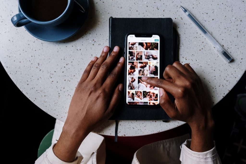 Eine Frau sitzt am Tisch und scrollt auf dem Telefon Instagram . 