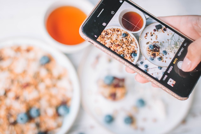 Woman taking an aesthetic photo of her meal to add to a food photo carousel.