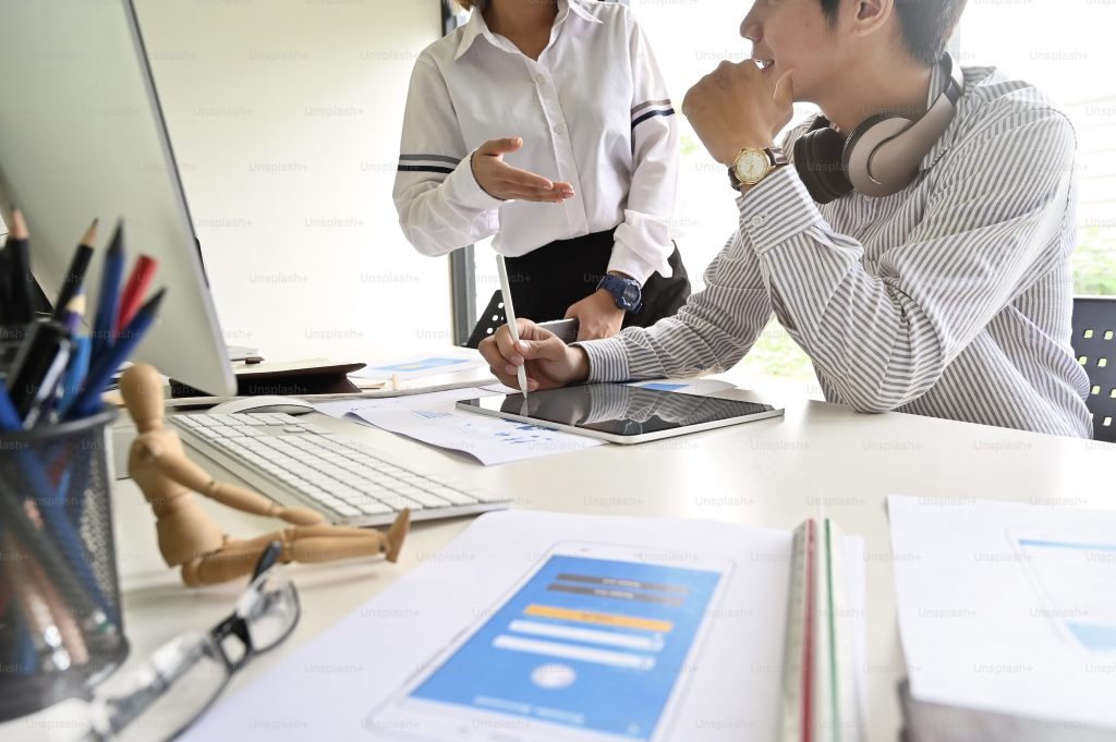 Boy with headphones, an Apple pencil, and an iPad talking to a woman