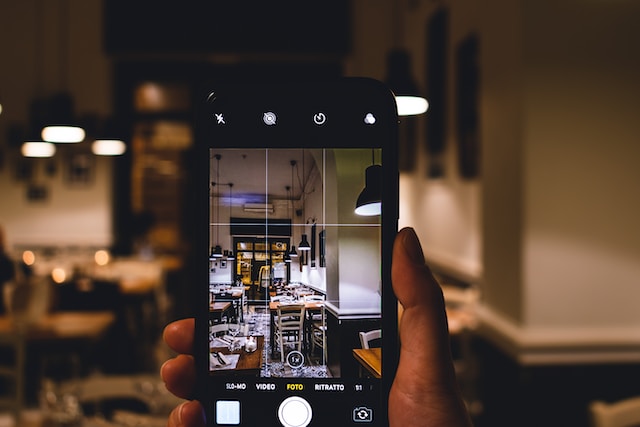Uma pessoa a fotografar o ambiente de um restaurante com o seu iPhone.
