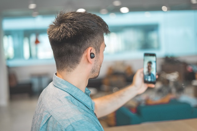 Hombre con auriculares negros tomándose un selfie con su smartphone.