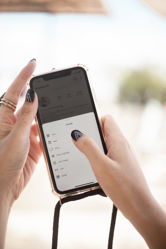 A woman with black nails clicking on the "create new post" button.