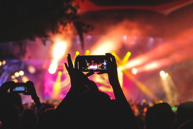 ユーザーは、ライブステージで演奏中のお気に入りのアーティストをスマートフォンで撮影する。