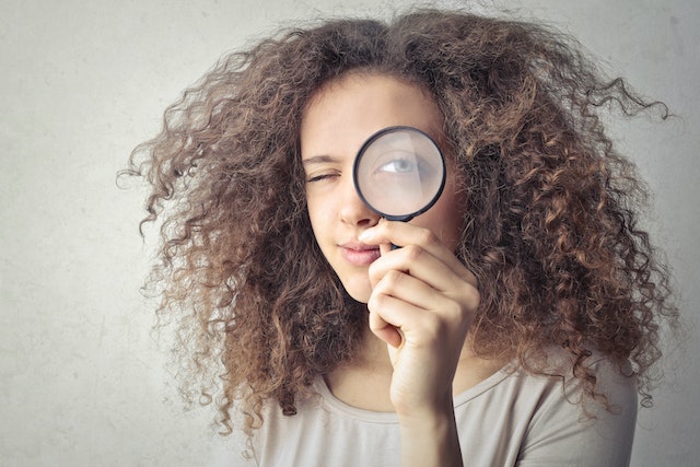 Femme tenant une loupe pour vérifier et regarder de plus près quelque chose.