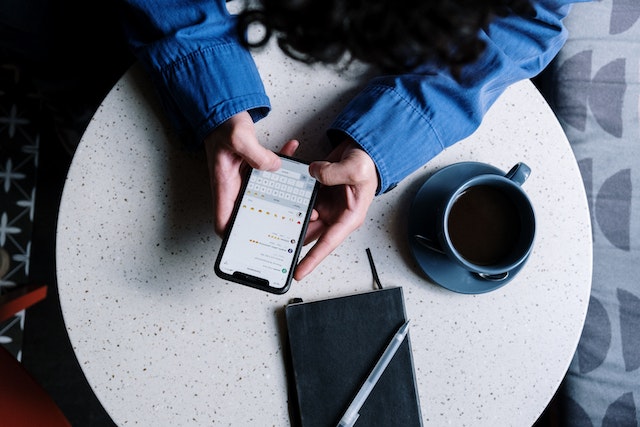 An aerial photo of a person sending an Instagram DM while sitting at a table in a cafe.