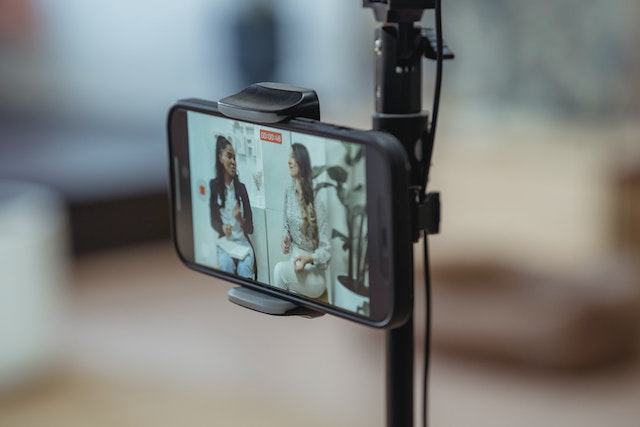 A phone is placed on a tripod to record two social media influencers. 