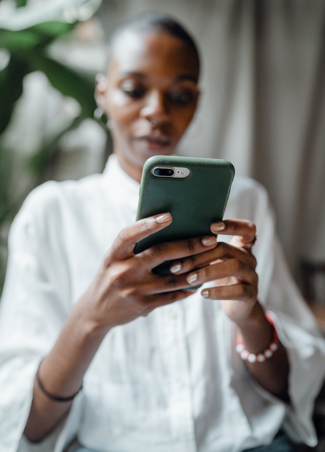 A woman holding her phone types hashtags in her Instagram post.