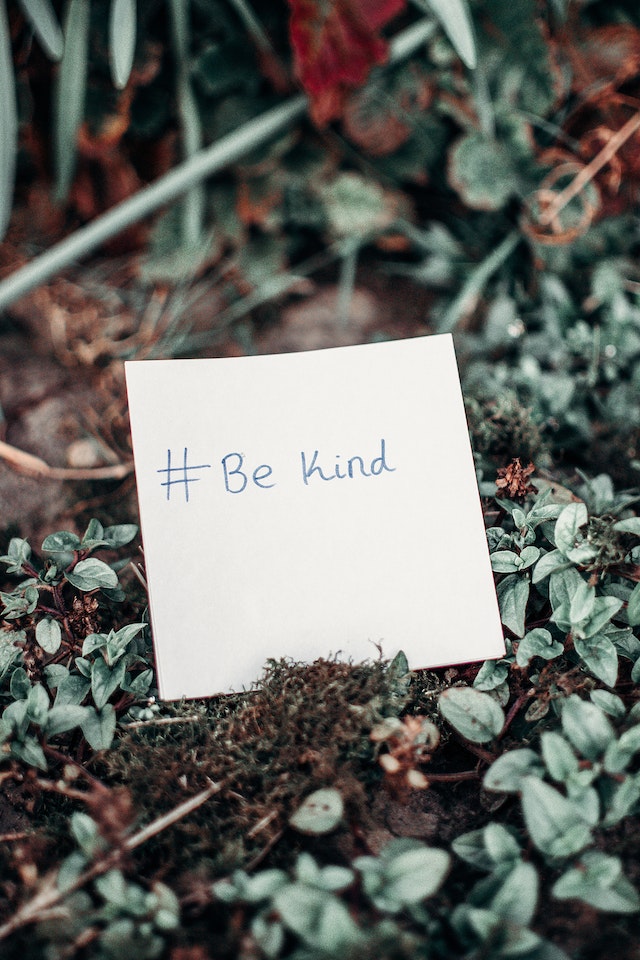 “#bekind” written on a square sheet of paper.