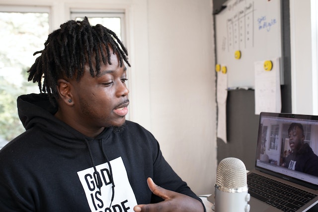 Influenceur parlant dans un microphone devant un ordinateur portable.