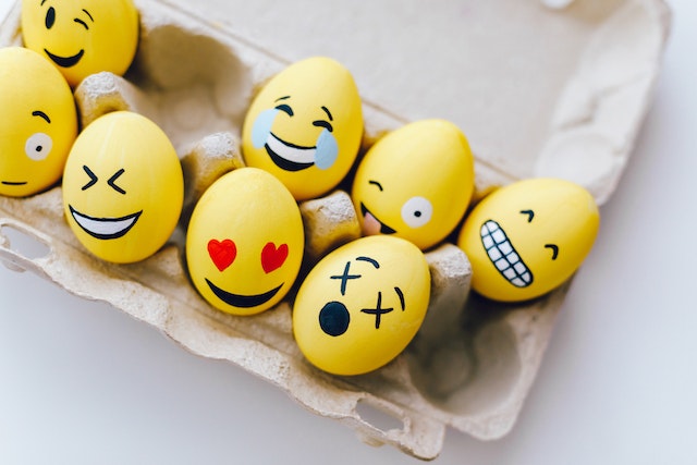 Ein Tablett mit gelben Eiern, die mit beliebten Emoji-Gesichtsausdrücken bemalt sind.