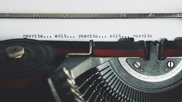 Machine à écrire avec les mots "rewrite" et "edit" répétés sur du papier blanc.