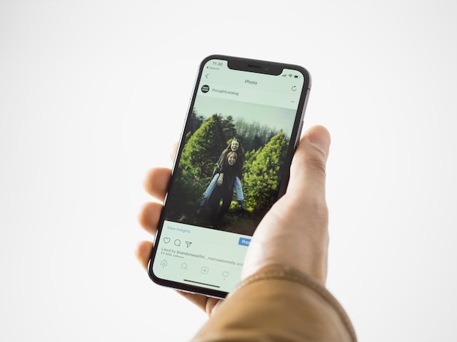 A person holding their phone viewing a photo of two friends on Instagram.