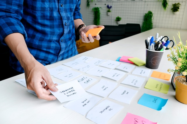 A man placing sticky notes on his desk. 