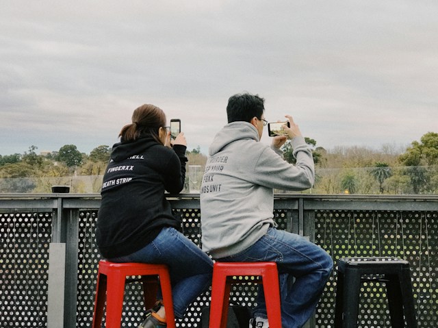 Duas pessoas estão a gravar um vídeo nos seus smartphones.