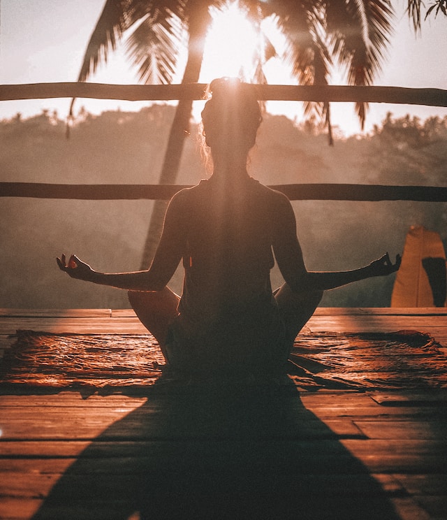 Silhouette einer Frau, die in einer Yoga-Pose sitzt.