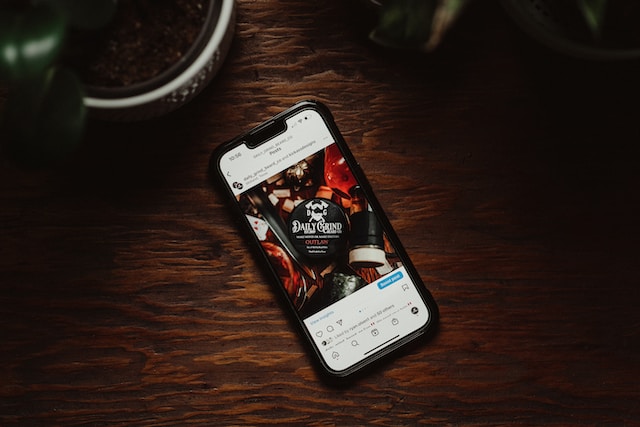 A picture of a smartphone displaying an Instagram post placed on a wooden table.