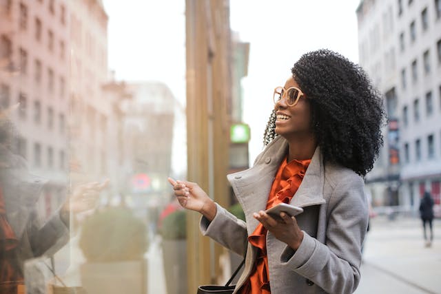 Mujer feliz con el teléfono en la mano sonriendo en la calle.