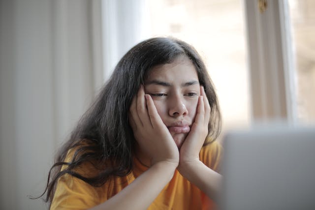 A business owner disappointedly looking at her laptop screen after getting shadowbanned for unethical IG automation.