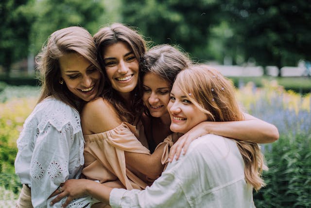 Un gruppo di amiche che sorridono e si abbracciano.