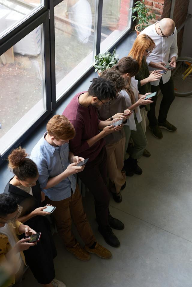 Een groep mensen die bij elkaar staan en naar hun social media feeds kijken.