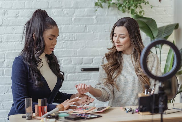 Two female influencers shooting a video for a paid partnership with a makeup label.