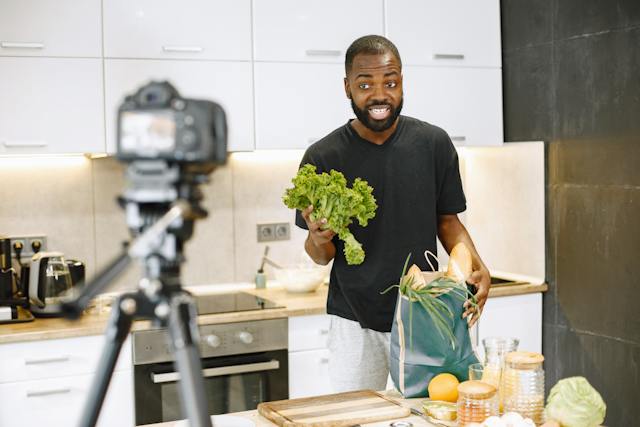 Um homem está a gravar um vídeo para o YouTube na cozinha.