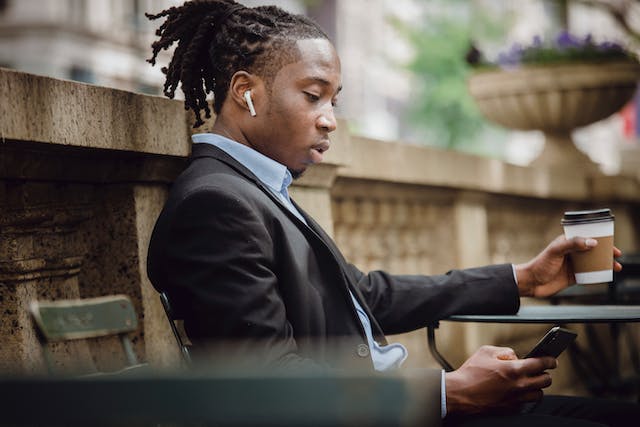 A man reading up on the news on Instagram on his phone while drinking coffee.