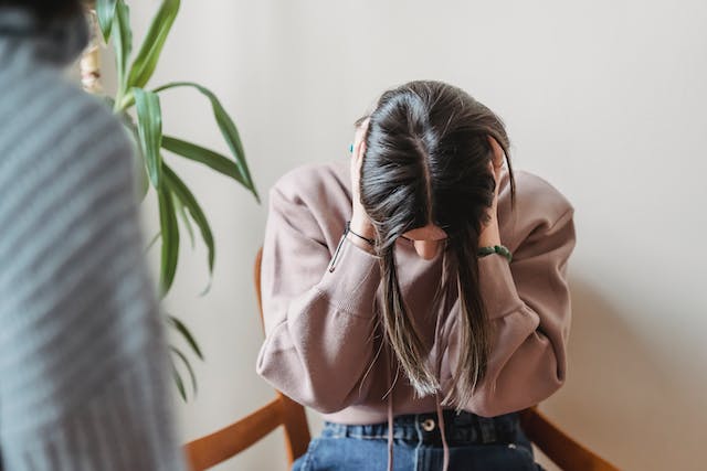 An agitated woman covering her ears after hearing bullies make personal attacks and comments about her.