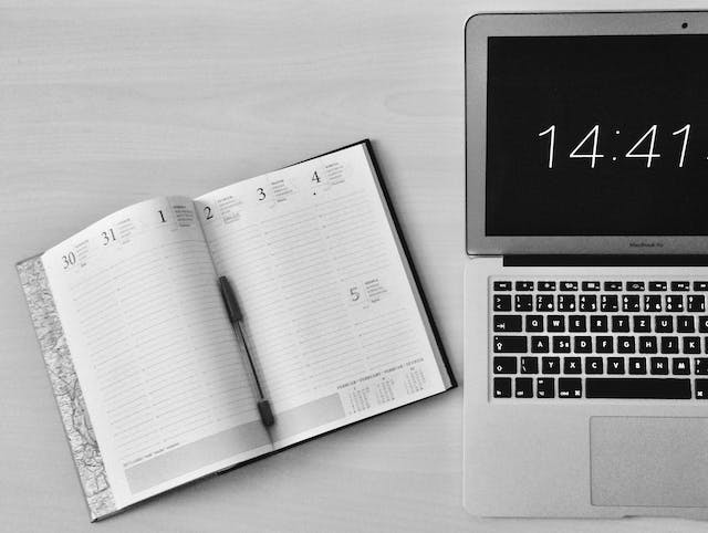 Un calendrier est ouvert à côté d'un ordinateur portable pour un créateur de contenu prêt à planifier son contenu.