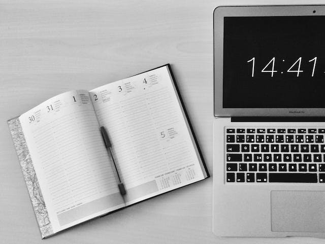 Un calendario è aperto accanto a un computer portatile per un creatore di contenuti pronto a pianificare i contenuti.