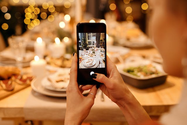 A woman taking a photo of her delicious Christmas dinner.