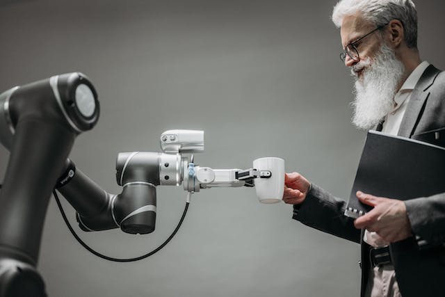 Un robot che automatizza il lavoro di preparazione del caffè per un uomo.