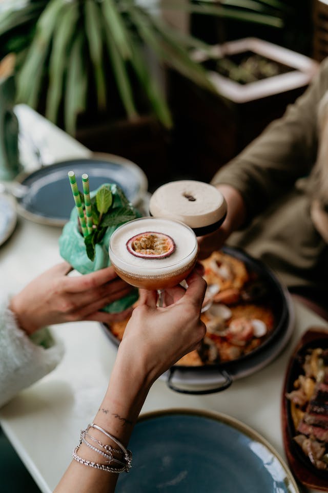 Los amigos hacen fotos de sus bebidas mientras chocan las copas.