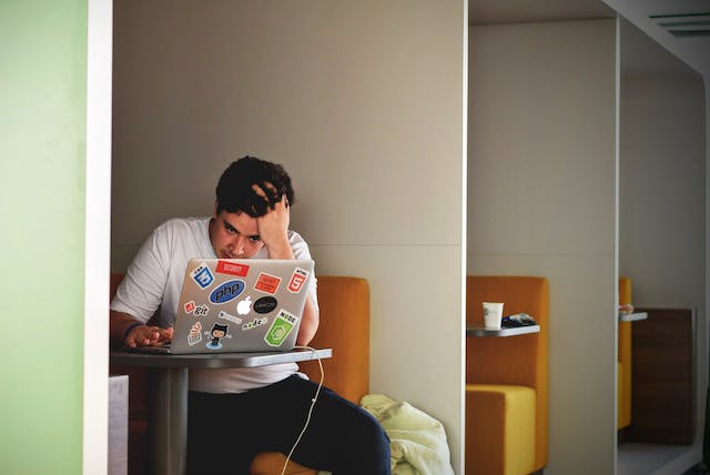 Homem de camisa branca a utilizar um computador portátil.