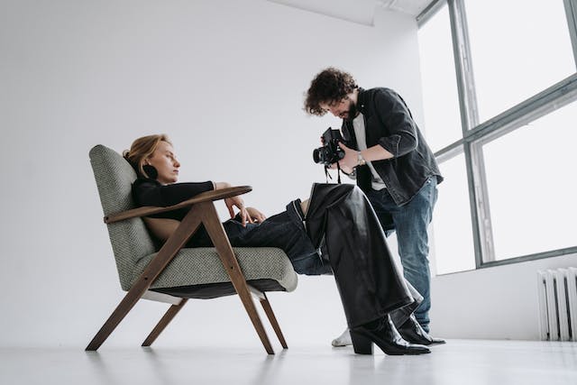 Ein Fotograf fotografiert eine Frau, die auf einem Stuhl sitzt.